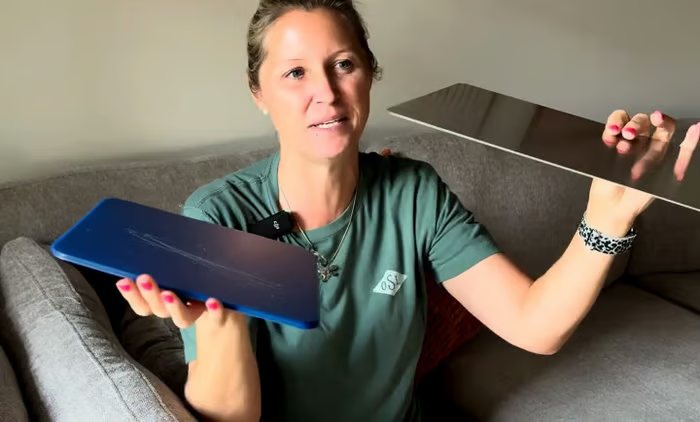 A woman holding the thin titanium cutting board up to show its profile